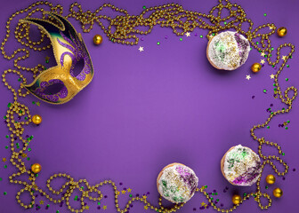 Obraz na płótnie Canvas Mardi Gras King Cake sufganiyot donuts, masquerade festival carnival mask, gold beads and golden, green, purple confetti on purple background.