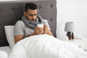 Obraz premium Cold And Flu. Portrait Of Sick Arab Man Drinking Tea In Bed