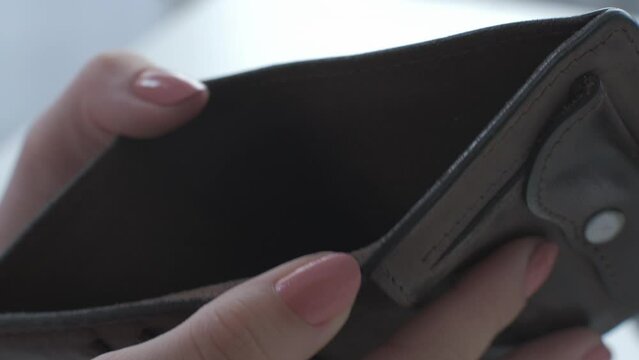 Empty wallet. Bankruptcy poverty. Financial crisis. Economic recession. Closeup of broke female hands showing open leather purse with no money.