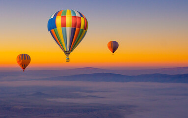 Fototapeta premium Hot air balloons in the sky during sunrise. Flying over the valley at Cappadocia, Anatolia, Turkey. Volcanic mountains in Goreme national park. Colourful hot air balloons.