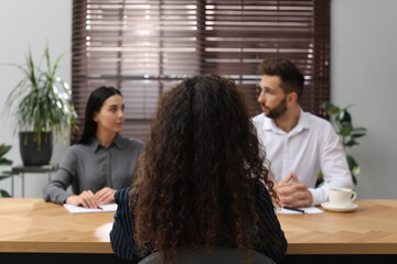 Coworkers conducting job interview with African American woman in office, back view. Racism concept