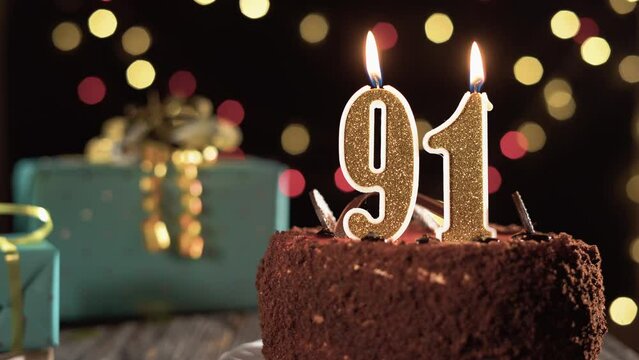 Birthday candle number ninety one on a sweet cake on the table, 91st birthday. Fire from the lighter, blow out the holiday candle.