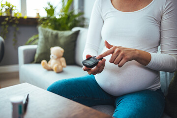 Pregnancy, health and glycemia concept - pregnant beautiful woman checking blood sugar level with...