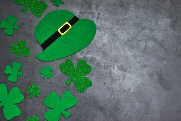 Flat lay composition with clover leaves and leprechaun hat on gray concrete background. Top view with copy space. St. Patrick's Day celebration. Holiday concept. Greeting card