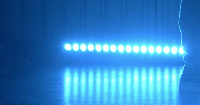 B-boy shows skills of break-dance legs moves on illuminated stage among crowd of people at party in night club closeup slow motion