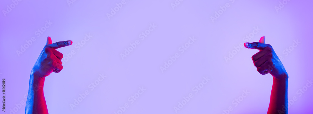 Poster unrecognizable young black man pointing at empty space in neon light, banner design