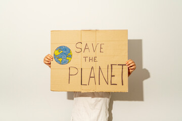 young girl holding a sign with the text save the planet in front of her face on a white background. Concept environment