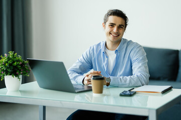 Happy young man works on his laptop to get all his business done early in the morning