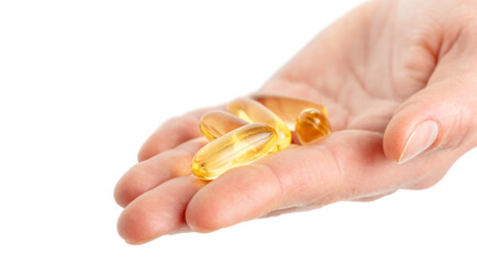 Close up of hand holding Omega 3 soft gel capsules on white background. Copy space