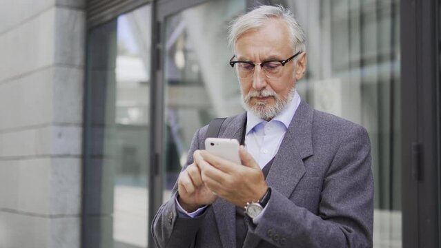 Curious mature man scrolling newsline on smartphone standing outdoor, uptodate