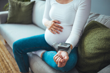 Pregnant woman measures blood pressure with an electronic tonometer. neuralgia during pregnancy,...