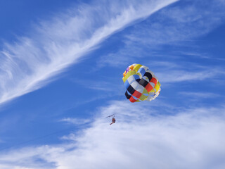 Active recreation at the resort, parasailing. Parachute on the background of a blue sky with clouds