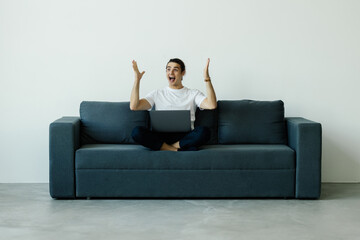 Upset desperate man having problems with wasting money, overspending,, scam and digital fraud. Frustrated disappointed shopaholic, bankrupt holding credit card at laptop, touching face