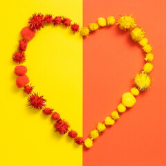 Heart symbol made of pompoms  on yellow and orange background. Valentine's Day or Love concept. Flat lay.