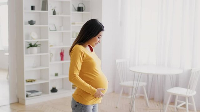 Happy Pregnancy Time. Side view of beautiful pregnant asian woman touching belly