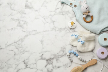 Cute baby stuff on white marble background, flat lay. Space for text