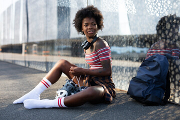 Young woman putting on rollerblades. Beautiful African woman with roller skates.