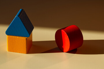 Children's wooden cubes of different shapes - square, circle, triangle. Block, cylinder, pyramid. Red, blue, yellow. Shadows and lights. On a white table. Geometric shapes and colors. House of cubes.