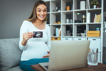 Fototapeta na wymiar Pregnancy, motherhood, people and medicine concept - happy pregnant woman with laptop computer having video call and showing ultrasound image at home