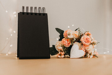 notebook with black sheets with copy space, a bouquet of flowers and a white heart