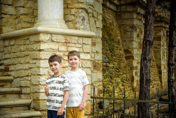 Obraz na płótnie Canvas Two little boys with modern haircuts near the stairs in colorful T-shirts and single tone pants. Concept of modern little boys
