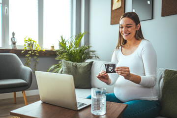 The beautiful pregnant woman has an online consultation with a doctor and keeps an ultrasound picture of her baby. She listens to advice and respects what the doctor tells her about her baby's health