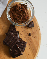 Cocoa powder in the plate and dark chocolate pieces on the food photography
