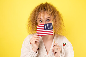 A young happy girl with a smile on her face holds an American flag in her hands. Symbol of patriotism and freedom.