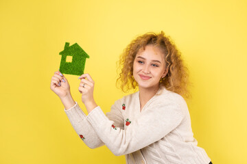 Fototapeta na wymiar Happy house buyer. A young girl holds a model of a green house in her hands. The concept of green energy, ecology.