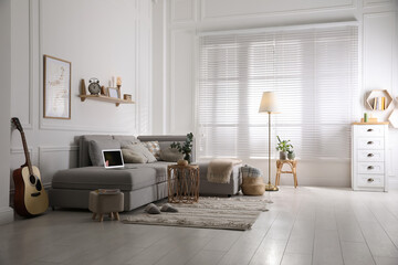 Living room with comfortable grey sofa and stylish interior elements near window