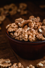 Fresh walnut kernels in a brown bowl on a rustic wooden background. Walnut kernels close up.