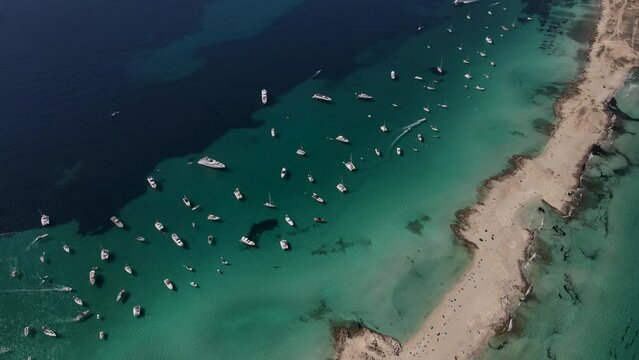 Aerial view of the white sandy beach of Formentera, moving in a forward direction at high speed. A perfect establishing shot of the entire beach.