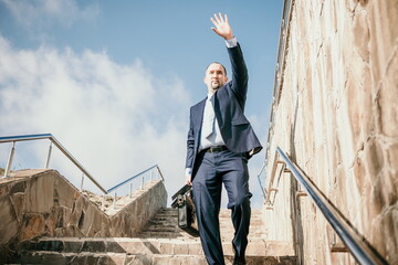 Confident middle age businessman with briefcase walking upstairs. Close-up of businessman wearing...