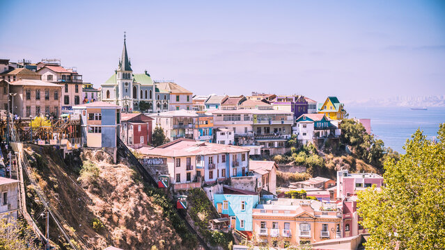 Die vielen, bunten H&auml;user, Stra&szlig;en sowie eine Kirche thronen oberhalb Valparaisos &uuml;ber dem blauen, pazifischen Ozean.