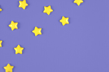 Cute yellow decorative stars sparse on trendy purple background with copy space for text. Top view, flat lay composition for mock up template design. Year color trend concept.