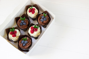Cupcakes  decorated with raspberry and blueberries  in delivery paper box. Sweet food delivery