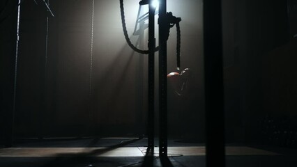 A woman throwing a ball up with squats in the gym. Silhouette of a woman throwing a ball over her head. Squats with a ball