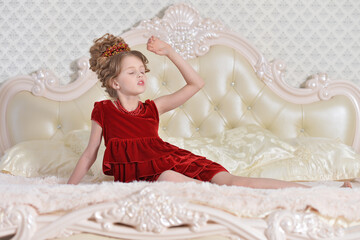 cute little  girl in red dress lying on bed