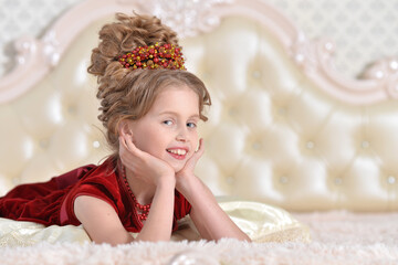 cute little  girl in red dress lying on bed