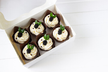 Cupcakes  decorated with fresh blackberry  in delivery paper box. Sweet food delivery. Fruits cup cakes, menu design or recipe background