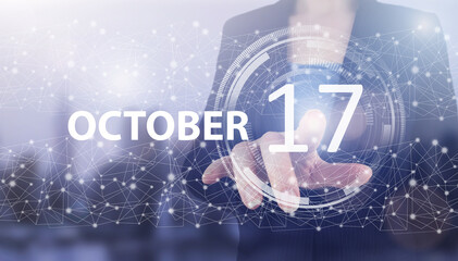 October 17th. Day 17 of month, Calendar date. Hand click luminous hologram calendar date on light blue town background. Autumn month, day of the year concept.