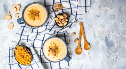 Two bowls of cream of corn soup with pistachios and croutons on top, vertical image, Vegan cuisine. Restaurant menu, dieting, cookbook recipe