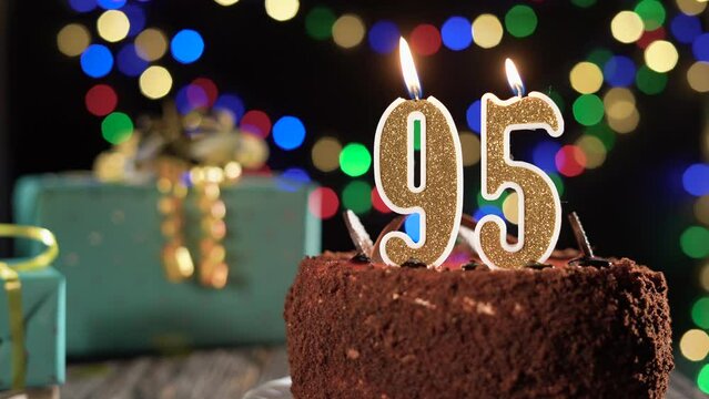 Number ninety-five birthday candle on a sweet cake on the table, 95th birthday. Fire from the lighter, blow out the holiday candle.