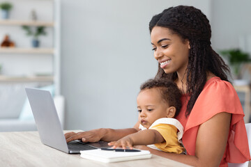 Portrait Of Black Woman With Baby On Hands Using Laptop At Home