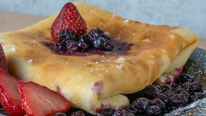 Classic american pancake with berry on black plate background. Crepe with blueberry and strawberry.