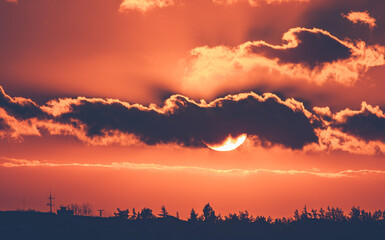 Sun sets in clouds, orange
