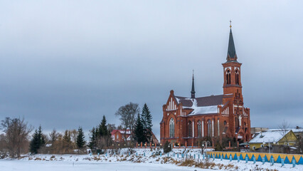 Catholic church of St. Anthony of Padua in Pastavy in winter. Monument of architecture in the neo-Gothic style. - obrazy, fototapety, plakaty