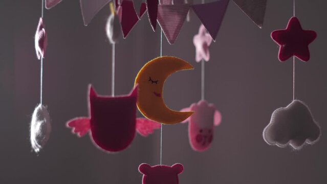 baby mobile with blue hand-stitched animal and bird toys with yellow moon on white wall background. spinning on the baby's crib in the room