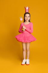 Cute girl in pink crown with magic wand on yellow background. Little princess © New Africa