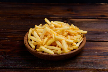 french fries in wooden bowl. French fries in a wooden bowl on a wooden background.